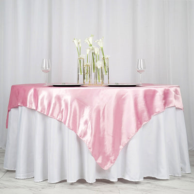 Pink satin tablecloth draped elegantly over a white table with floral centerpiece.