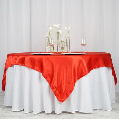 Red satin tablecloth draped over a white table with floral centerpieces.