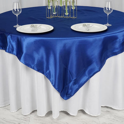 Blue satin tablecloth draped over a white table with plates and glasses.