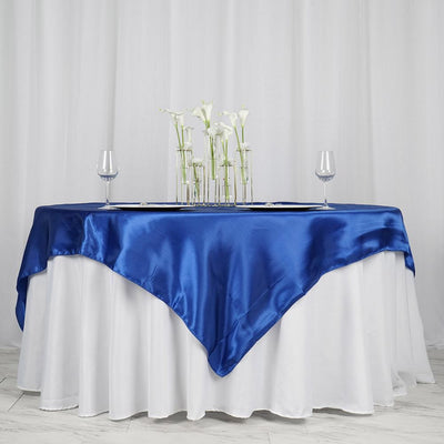 Blue satin tablecloth draped elegantly over a white table with decorative flowers.