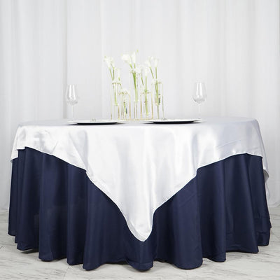 Elegant navy and silver tablecloth draped over a round table with glassware and flowers.
