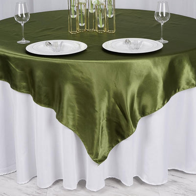 Green satin tablecloth draped over a round table with elegant dinnerware.