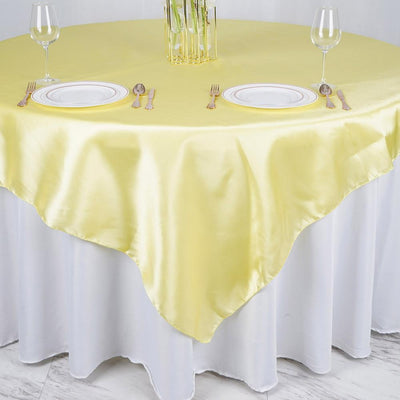 Yellow satin tablecloth draped over a round table set for dining.