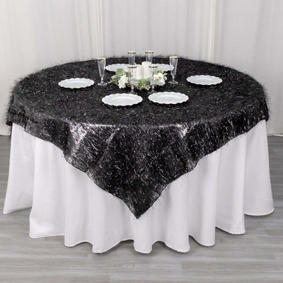 Round black tablecloth with silver accents on a white table setting.