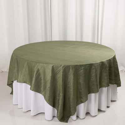 Round olive green tablecloth on a white table.