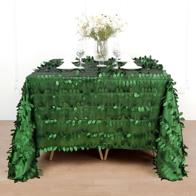 Green leaf tablecloth draping over a table set for dining.