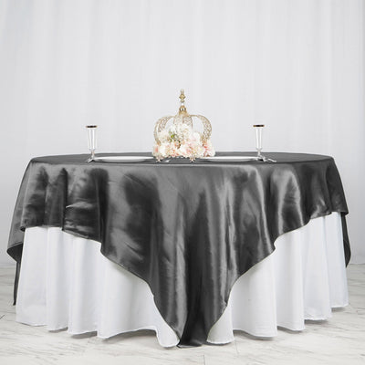 Elegant black satin tablecloth draped on a white table with decorative crown centerpiece.