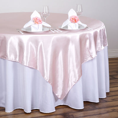 Elegant pink satin tablecloth with white napkins and floral accents on a dining table.