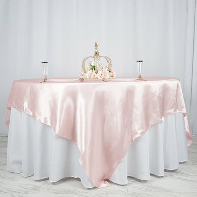 Elegant pink satin tablecloth draped over a white table with floral centerpiece.