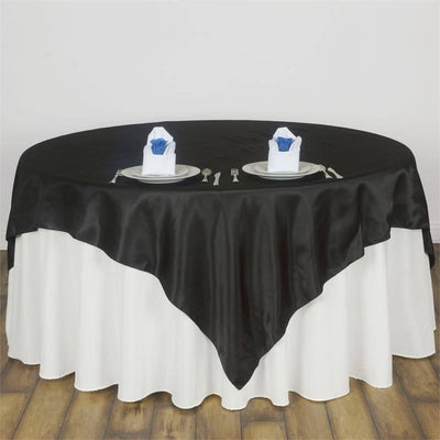 Black satin tablecloth draped elegantly over a white table with dining setup.