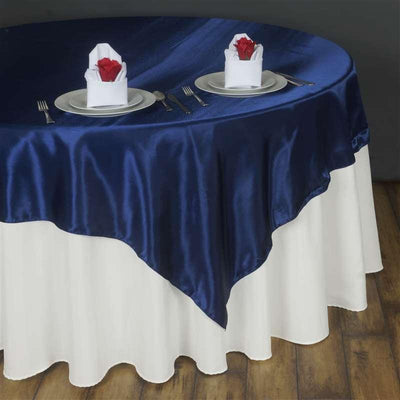 Elegant navy blue satin tablecloth draping over a white table with decorative napkins.