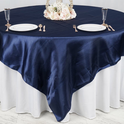 Navy satin tablecloth draped over a round table with elegant dinnerware.