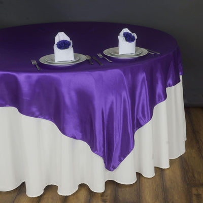 Purple satin tablecloth draped elegantly over a white table, set for dining.