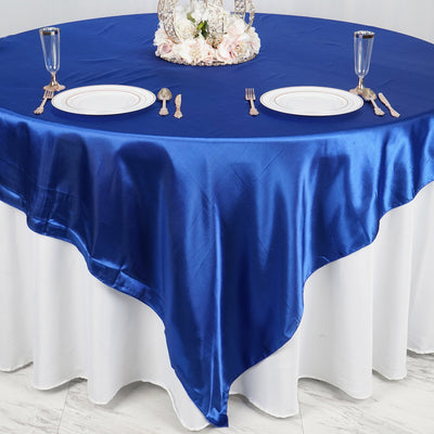 Blue satin tablecloth draped elegantly over a round table set for dining.