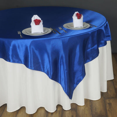 Blue satin tablecloth with white pleated table skirt and elegant napkin presentation.