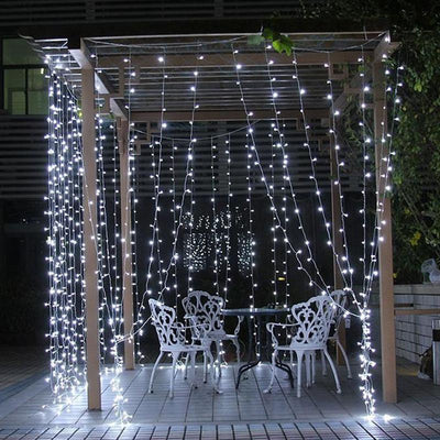 Outdoor white string lights illuminating a pergola with seating area.