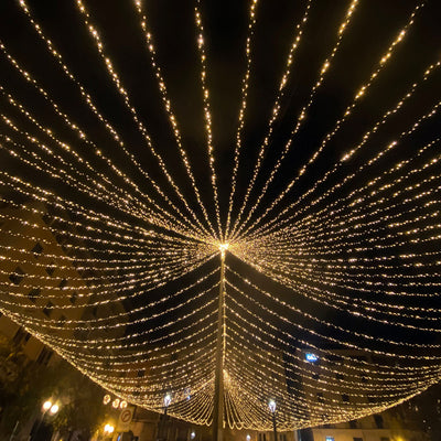 Illuminated string lights creating a starburst effect in a night scene.