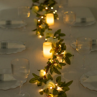 Elegant dining table setting with candles and greenery accents.