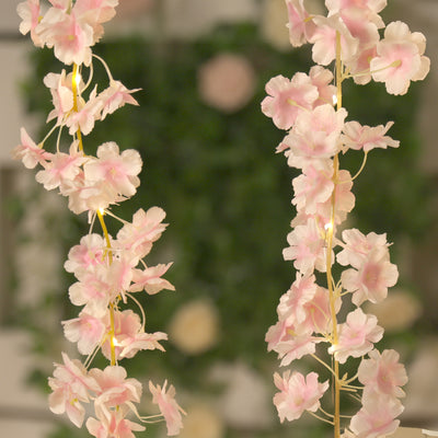 Pink flower garland with lights on a decorative backdrop.