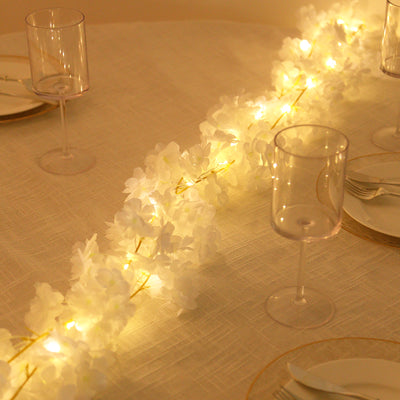 Floral string lights on a table setting with elegant glassware.
