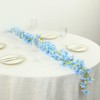 Blue floral table runner on a set dining table with clear glassware.