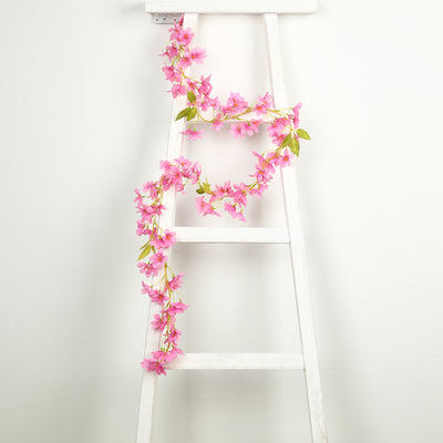Pink floral garland draped on a white ladder against a plain background.