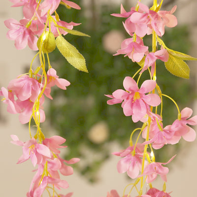 Artificial pink flower garland with green leaves, perfect for decor.