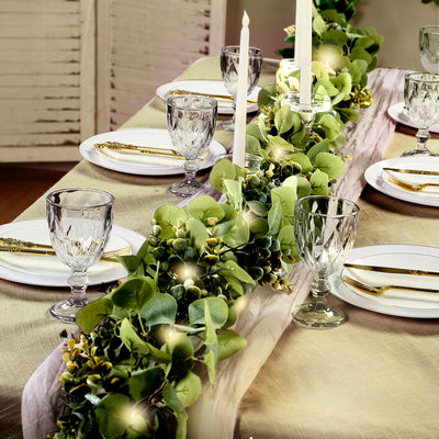 Elegant table setting with greenery, candles, and glassware for a festive dining experience.