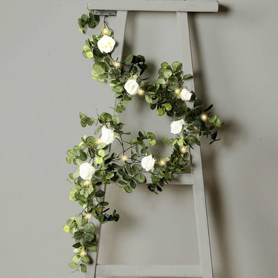 LED flower string lights on a decorative ladder with greenery.