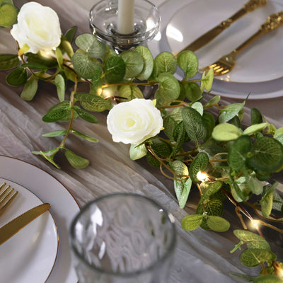 Elegant floral table centerpiece with greenery and soft white roses.