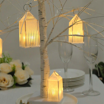 Decorative lanterns hanging from a tree centerpiece with soft glowing light.