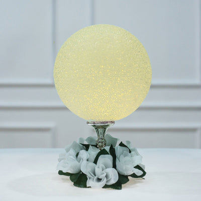 Glowing decorative orb lamp on a floral base.