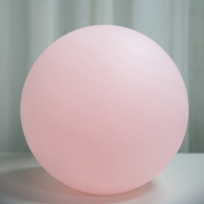 Pink glass orb lamp on a white surface