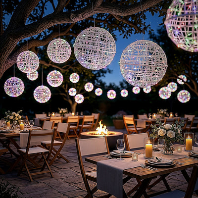 Outdoor dining setup with glowing decorative orbs under a tree at night.