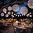 Outdoor dining setup with glowing decorative orbs under a tree at night.
