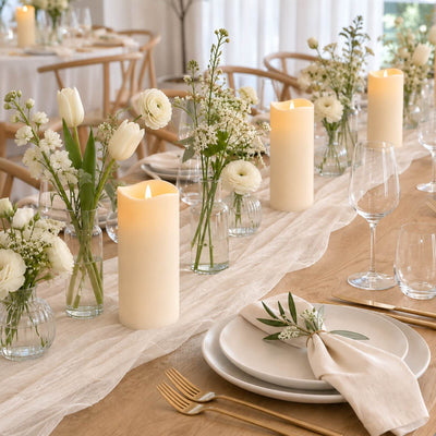 Elegant white floral wedding table setting with candles and gold flatware