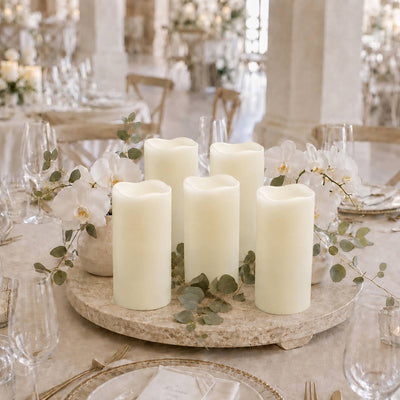 Elegant ivory pillar candle centerpiece with white orchids and eucalyptus on a reception table