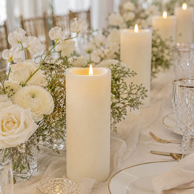 Elegant white floral wedding table centerpiece with lit pillar candles