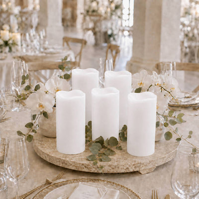 Elegant wedding table centerpiece with white pillar candles and orchids