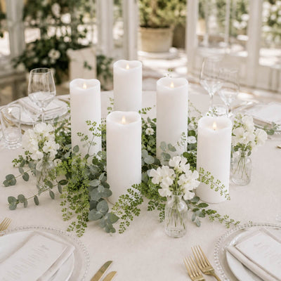 Elegant white candle and greenery wedding table centerpiece with floral accents