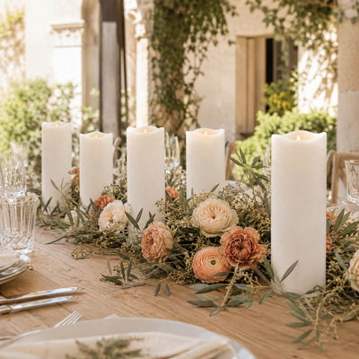 Elegant outdoor dining table with white pillar candles and floral centerpiece