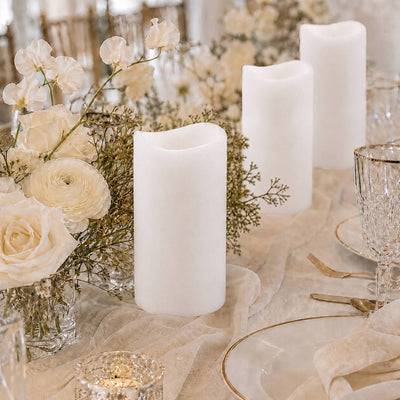 Elegant white pillar candles and cream floral table centerpiece on a wedding table