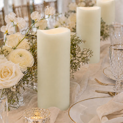 Elegant white candle centerpiece with roses and gold tableware at a wedding table