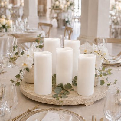 Elegant wedding table centerpiece with white candles, orchids, and greenery