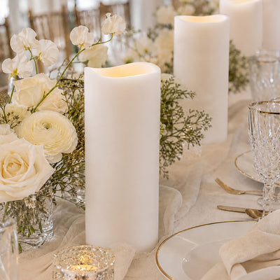 Elegant white floral wedding table centerpiece with pillar candles and gold accents