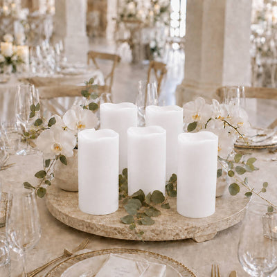 Elegant white pillar candles and orchids centerpiece on a luxury wedding table