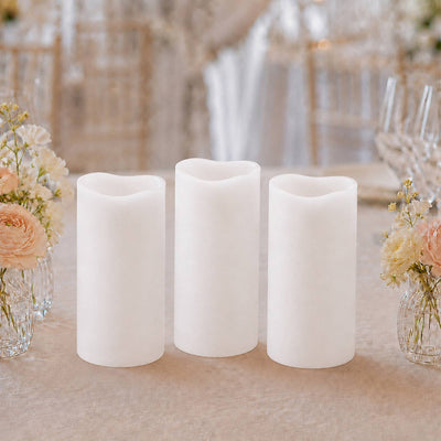 Three white flameless pillar candles with floral wedding table decor