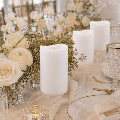 Elegant white floral table centerpiece with pillar candles and gold accents