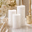 Elegant white flameless candles with roses and gold decor in a soft romantic setting