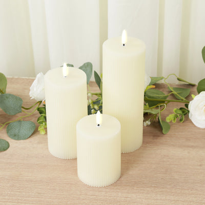 Set of three ribbed ivory candles with LED flames and greenery accents.